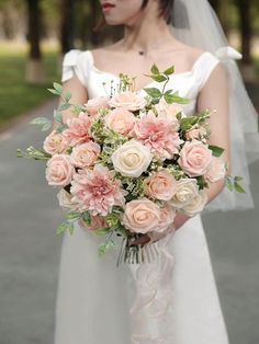 a woman in a wedding dress holding a bridal bouquet with pink and white flowers