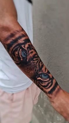 a man's arm with a tiger tattoo on it and blue eyes in the center