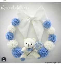 a white teddy bear with blue and white pom - poms around it's neck