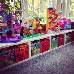 the toys are lined up on the shelf in the playroom with plastic bins