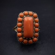 Ancient Romans believed that wearing coral would protect children, and hung pieces of it around their necks. Women wore it as a charm against sterility. It was thought to quiet tempests and insure that the wearer would never be struck by lightening. The stone became very popular during the Victorian Era, where it was incorporated, usually by Italian jewelers, into all forms of decorative wear. The bright, warm hue and the lore of protection appealed to the symbolic trends of the time. This gorgeous and eye-catching ring has the coral turned up to eleven! A long rectangular cabochon is set in 10k yellow gold, studded with even more coral! Details (approximate) Size: 7.5 Dimensions: Ring top is 2cm at widest point  Weight: 7.5 grams Materials: Gold, Coral Metal: 10K yellow gold Marks: None C Antique Orange Gemstone Jewelry, Vintage Oval Coral Jewelry, Vintage Coral Oval Jewelry, Antique Oval Orange Jewelry, Antique Orange Oval Jewelry, Vintage Coral Jewelry For Anniversary, Coral Vintage Jewelry For Anniversary, Orange Oval Antique Jewelry, Antique Untreated Jewelry Gift