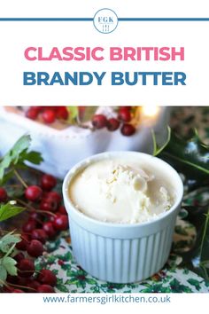 a white bowl filled with butter next to holly leaves and berries on a green table cloth