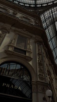 there is a clock on the side of an old building with glass walls and windows