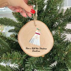 a hand holding a christmas ornament on top of a tree