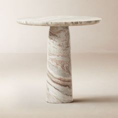 a marble table with a white base and brown veining on the top, against a beige background