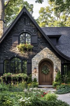 a stone house with black shutters and a wreath on it's front door