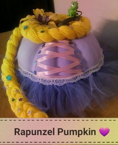 a purple and yellow hat on top of a wooden table next to a sign that says rappunzel pumpkin