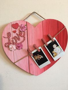 a wooden heart with two pictures hanging from it's sides and the word love spelled on