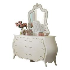 a white dresser with a mirror on top of it and flowers in vases next to it