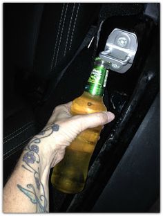 a hand holding a beer bottle in the back seat of a car