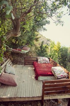 a wooden deck with two beds and hammock hanging from the trees above it