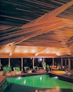 an indoor swimming pool with lounge chairs and lights on the ceiling is lit up at night