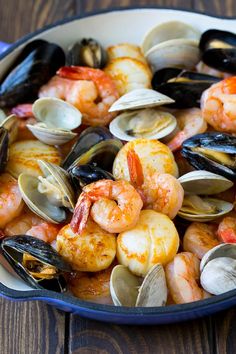 a pan filled with seafood and mussels on top of a wooden table