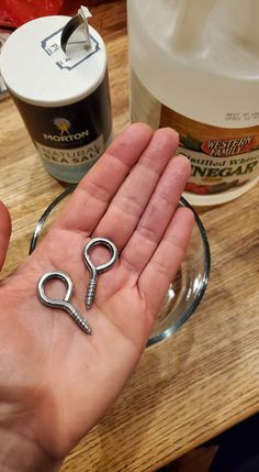 a hand holding a pair of scissors on top of a wooden table