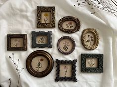 there are many different frames on the table together, including one with flowers in them