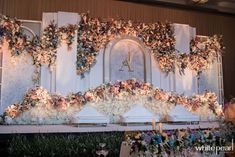 an elaborately decorated stage with flowers and greenery on the wall for a wedding ceremony