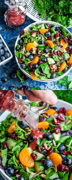 a person pouring dressing onto a salad in a bowl with oranges, blueberries and spinach