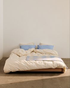 an unmade bed with blue and white pillows