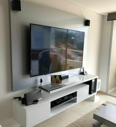 a flat screen tv sitting on top of a white entertainment center in a living room