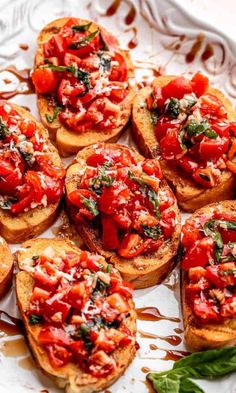 several pieces of bread with tomato sauce and basil on them sitting on a white plate