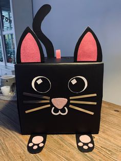 a black box with a cat's face painted on the front and paws sticking out