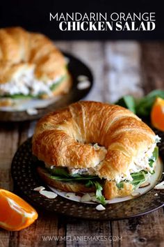 a croissant sandwich on a plate with orange slices