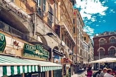 people are walking down the street in an old european city with many shops and restaurants