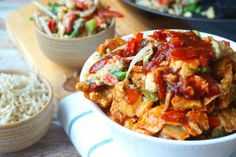 a white bowl filled with food next to rice