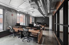 an empty office with desks and chairs in front of large windows overlooking the city