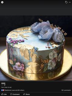 a blue and gold cake with flowers on it