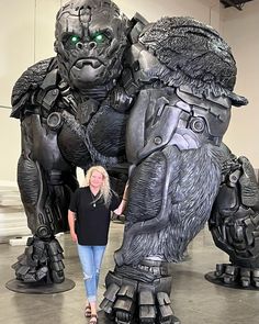 a woman standing next to a giant gorilla statue