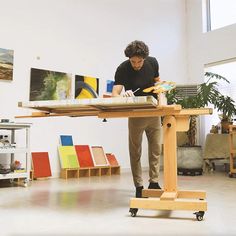 a man standing at a table working on a piece of art in an art studio