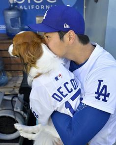 a baseball player kissing his dog in the dugout