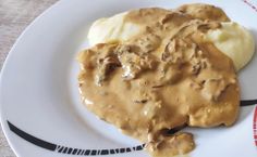 a white plate topped with mashed potatoes and gravy