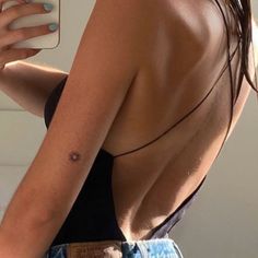 a woman with a tattoo on her back holding a cell phone