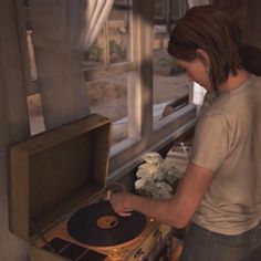 a woman standing next to a record player in front of a window with flowers on it