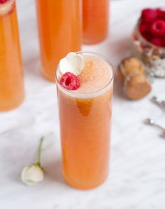 three glasses filled with drinks on top of a table