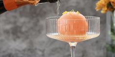 a person pours wine into a glass with an orange garnish in it