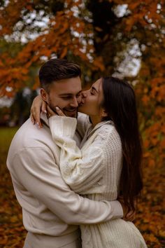 a man and woman are kissing in the fall leaves