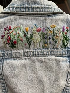 the back of a jean jacket with flowers embroidered on it