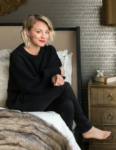 a woman sitting on top of a bed next to a night stand and nightstands