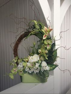 a green basket filled with flowers on top of a white shelf