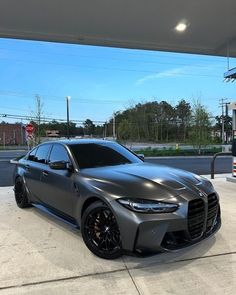 a gray sports car parked in front of a gas station with no one around it