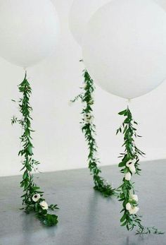 two white balloons with flowers and greenery hanging from them