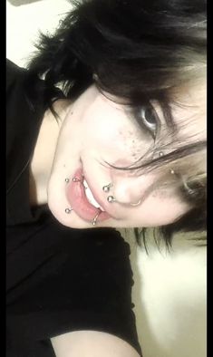 a woman with piercings on her nose and black shirt is posing for the camera