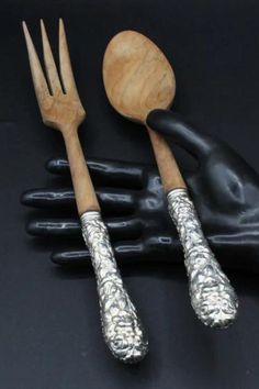 three forks and two spoons are sitting next to each other on a black surface