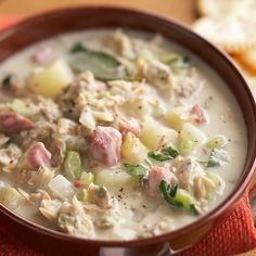 a bowl of soup with meat, potatoes and green beans on a red cloth next to bread