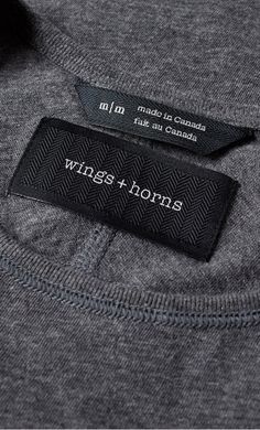 a label on the back of a gray shirt that says wings + horns in white lettering