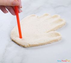 a hand holding an orange plastic straw over a cookie