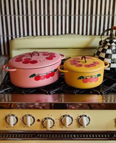 two colorful pots are sitting on top of the stove, next to an old fashioned tea kettle